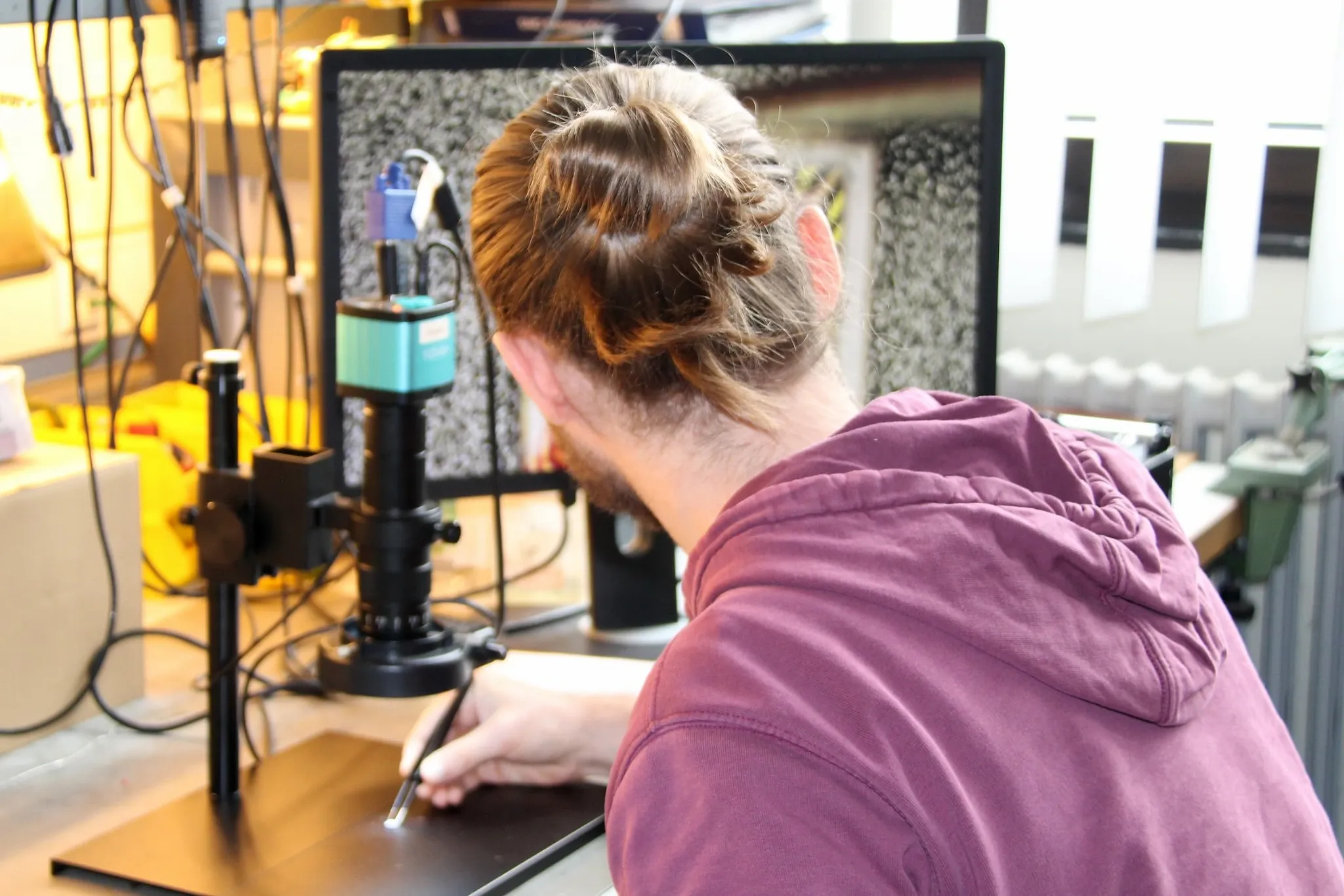 An iQrypto engineer working with a microscope at the laboratory bench