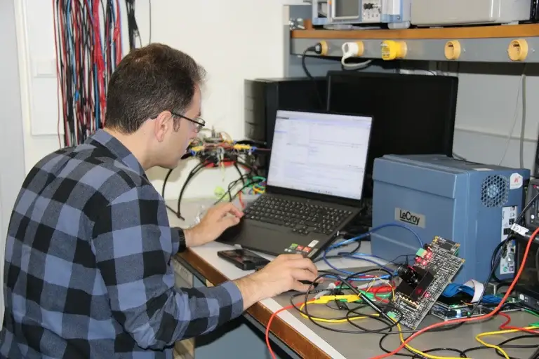 Engineer working on DAQ board with connected instruments and software interface on a laptop